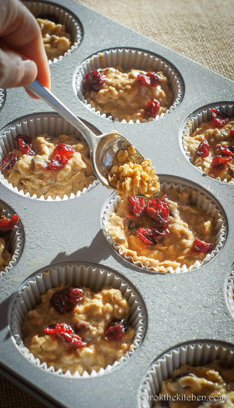 filling baking tins with cranberry oat muffin batter